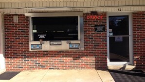 A brick building with a service window and an office door. - Voyager Inn (Aliceville)