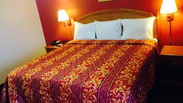 A hotel room with a large bed, two bedside lamps, and a nightstand with a phone.