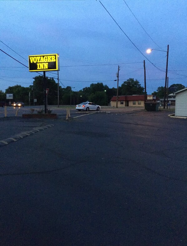 Un panneau de signalisation indiquant le « Voyager Inn » et une voiture blanche garée sur le bord de la route.