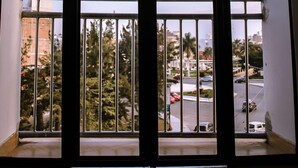 A room with a large window overlooking a street with cars and palm trees. - Musky Hs & Suites (Chiclayo)