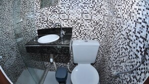 A bathroom with a tiled mosaic wall, a white toilet, a sink with a black countertop, and a shower area.