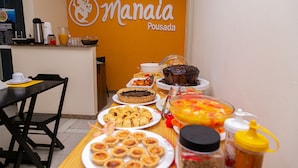 Une table de buffet proposant divers plats et une pancarte indiquant « Manaia Pousada ».