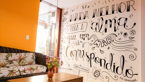 Une pièce comprenant un canapé, une table ornée d’un vase de fleurs et un mur décoré d’une fresque.