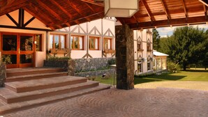 A stone staircase leading to a wooden door, a covered patio area, and a view of a well-maintained lawn and trees.