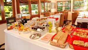A buffet setup with various food items and beverages, including pastries, fruits, and a selection of drinks.
