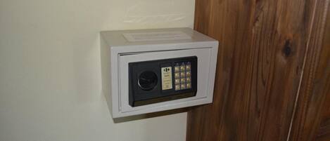 A white security box with a keypad and a lock on a wall.