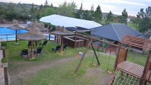 A pool area with a swing set, chairs, and thatched umbrellas. - Terrazas de Colon (Colon)