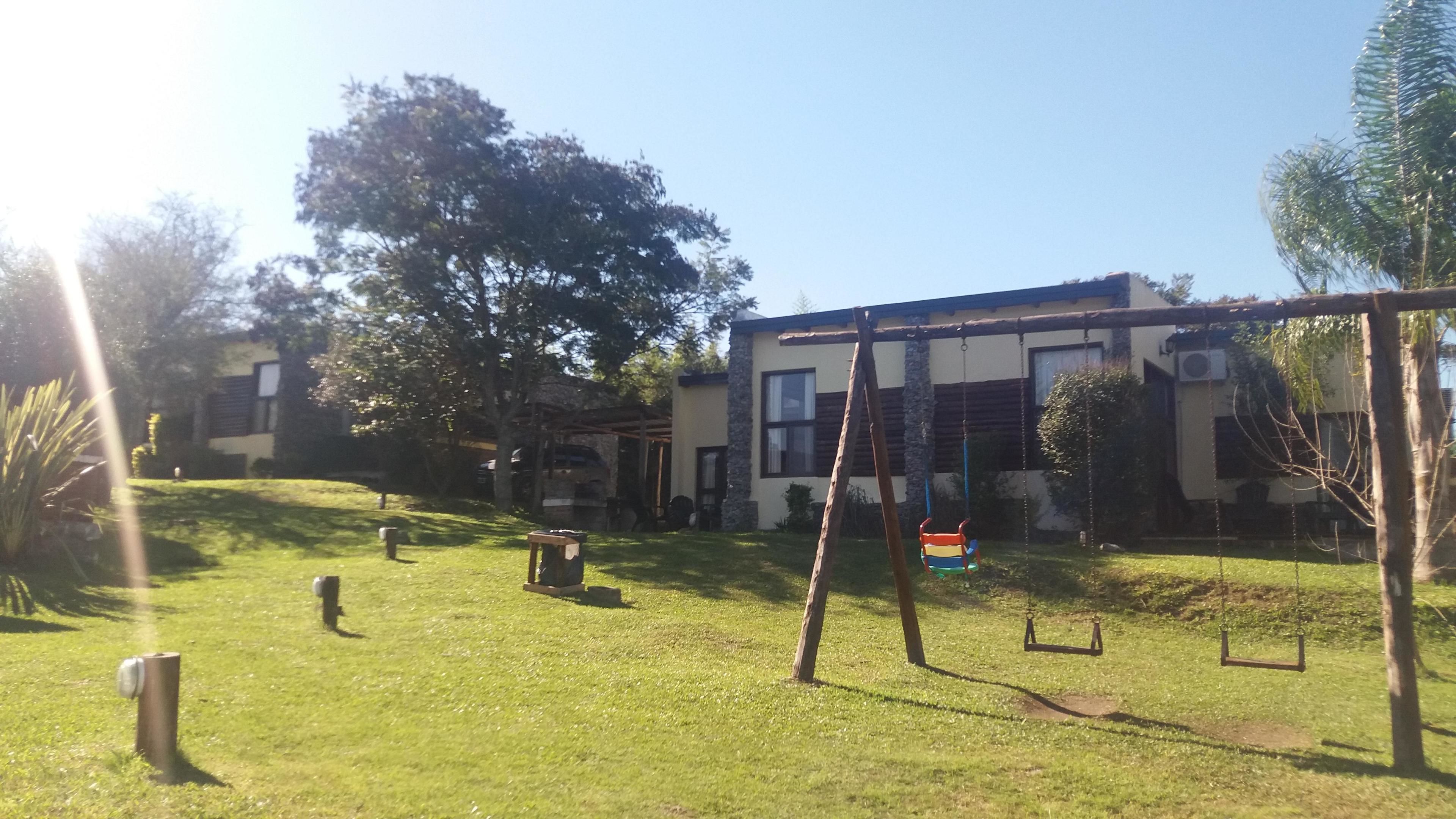 Una zona residencial con césped, un columpio y un edificio de fachada de piedra.