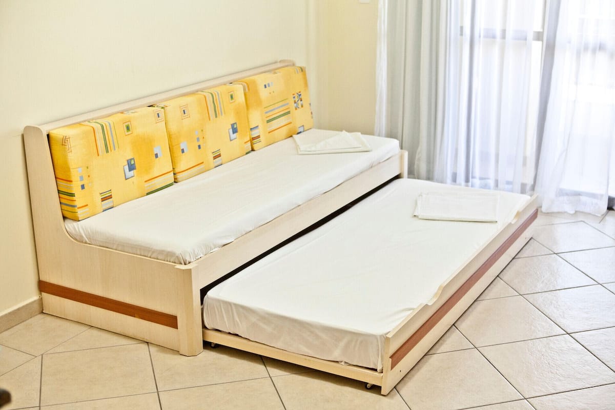 A single bed with a wooden frame and a mattress with a white sheet.
