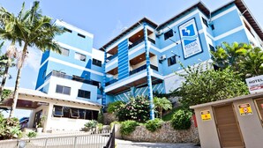 A multi-story building with a blue and white color scheme, featuring a reception area and a sign indicating it is a hotel. - Bombinhas Praia Apart Hotel - Unidade Bem Te Vi (Bombinhas)