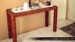Un baño con tocador de madera, un espejo, un jarrón con flores y una bandeja con artículos de aseo.