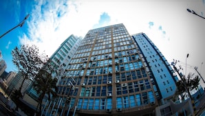 Un edificio alto con varios pisos, ventanas grandes y unidades de aire acondicionado.