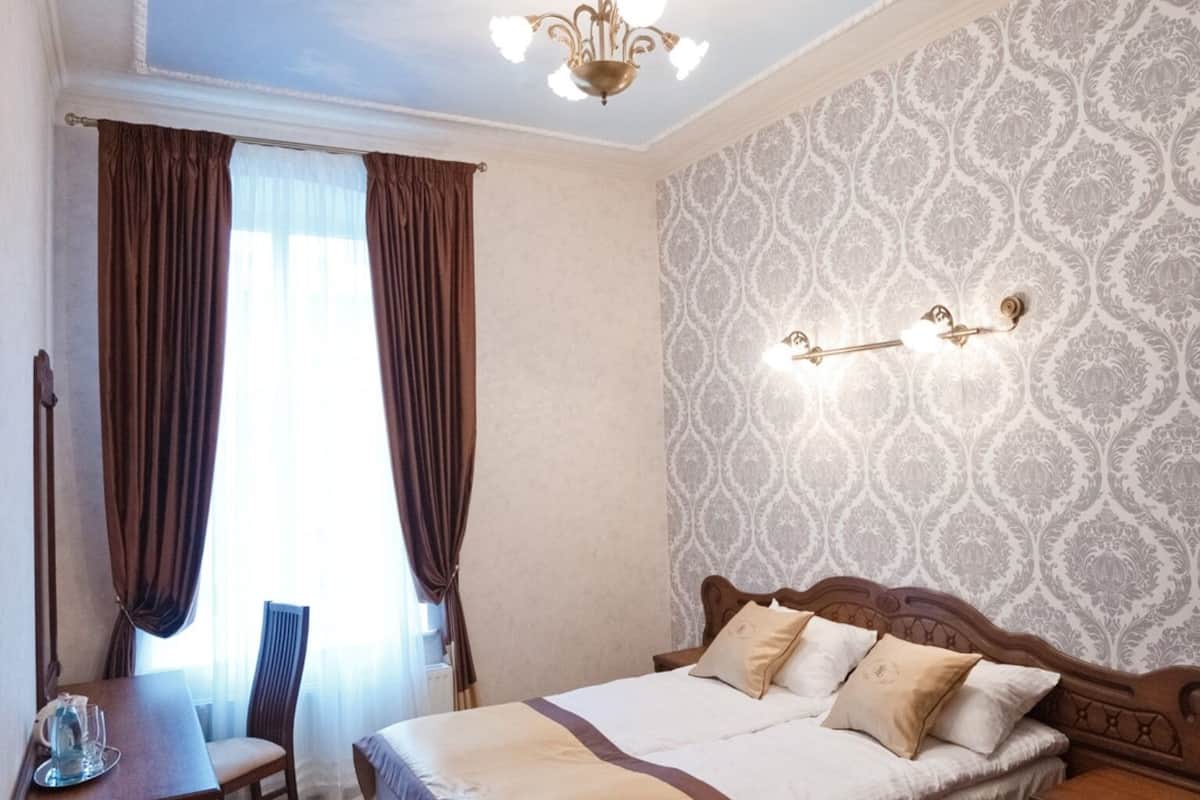 Ein Hotelzimmer mit einem großen Bett, einem Schreibtisch, einem Sessel und einer Decke mit einer dekorativen Leuchte.
