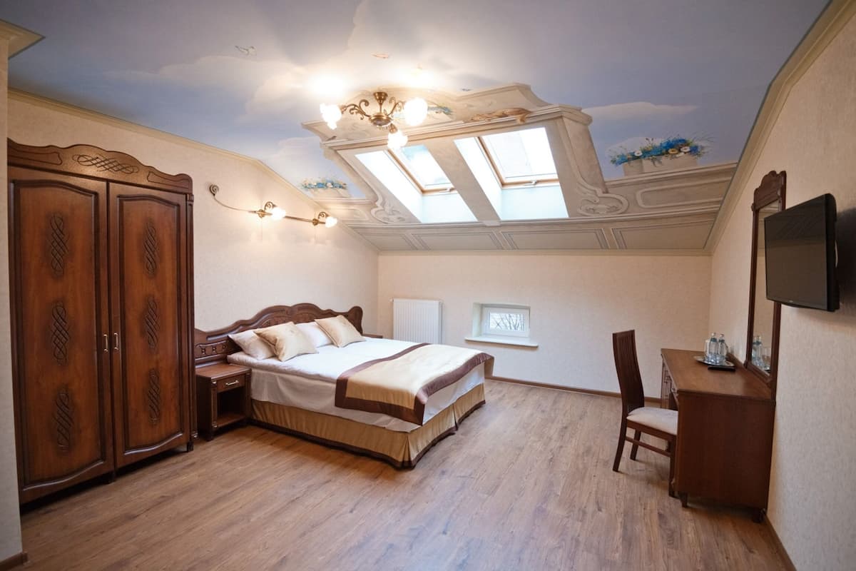 Ein Schlafzimmer mit einem Holzbett, einem Schreibtisch, einem Stuhl, einem Kleiderschrank und einem Fernseher an der Wand.