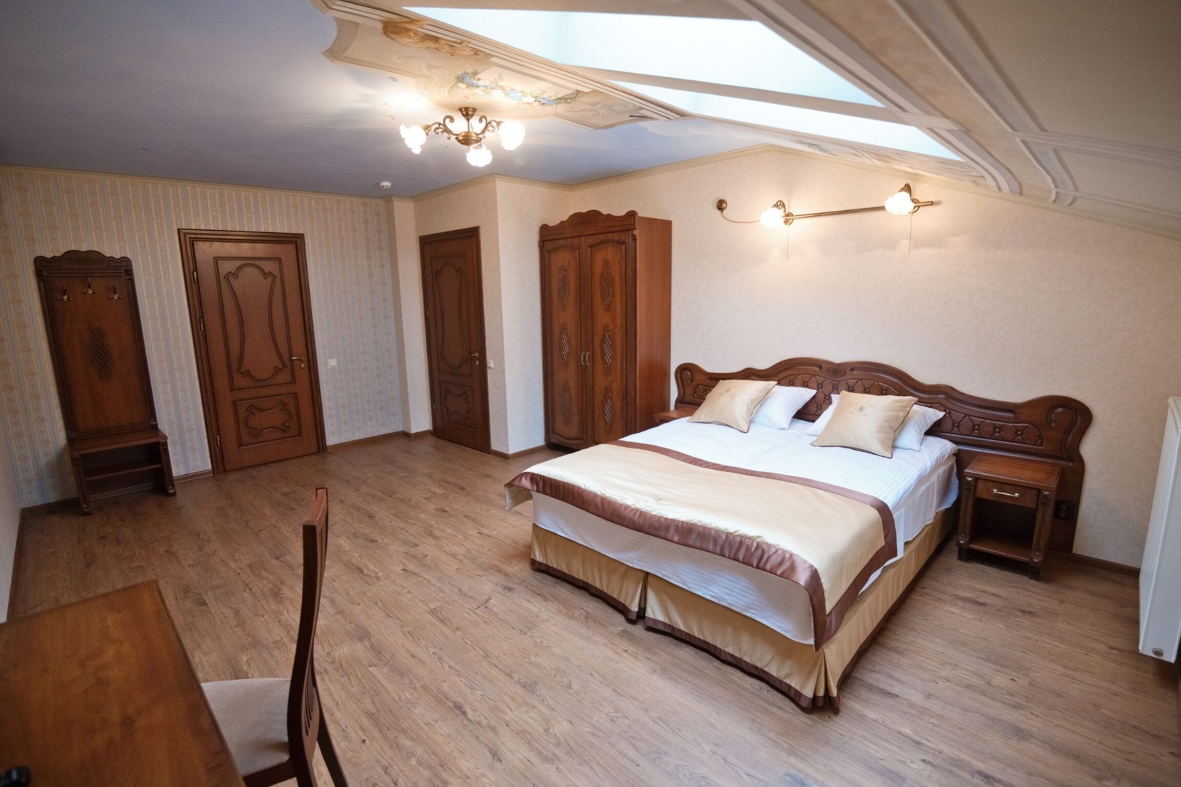 A bedroom with a large bed, wooden wardrobe, and a desk.