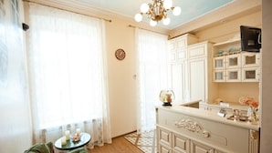 A room with a green sofa, a small table with candles, a chandelier, and a vintage-style vanity with a mirror and cabinets. - Guest House Inn Lviv (Lviv)