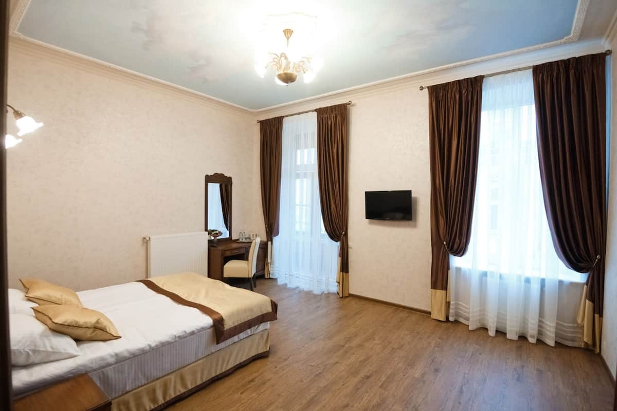 Ein Hotelzimmer mit Bett, Schreibtisch, Stuhl, Fernseher und Vorhängen.