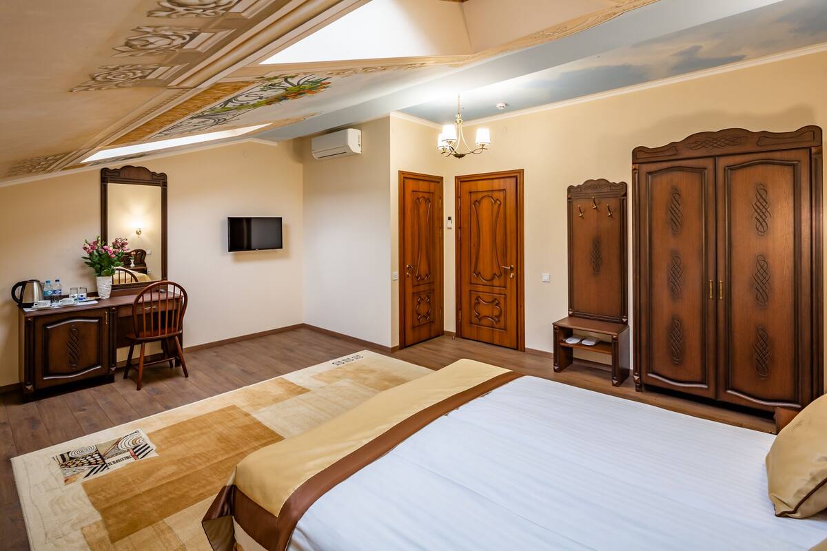 Ein Schlafzimmer mit einem Bett, einem Schreibtisch mit Stuhl, einem Fernseher und einem Kleiderschrank.