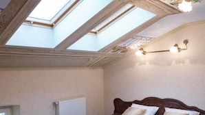 A bedroom with a skylight, a radiator, and a bed with a headboard. - Guest House Inn Lviv (Lviv)