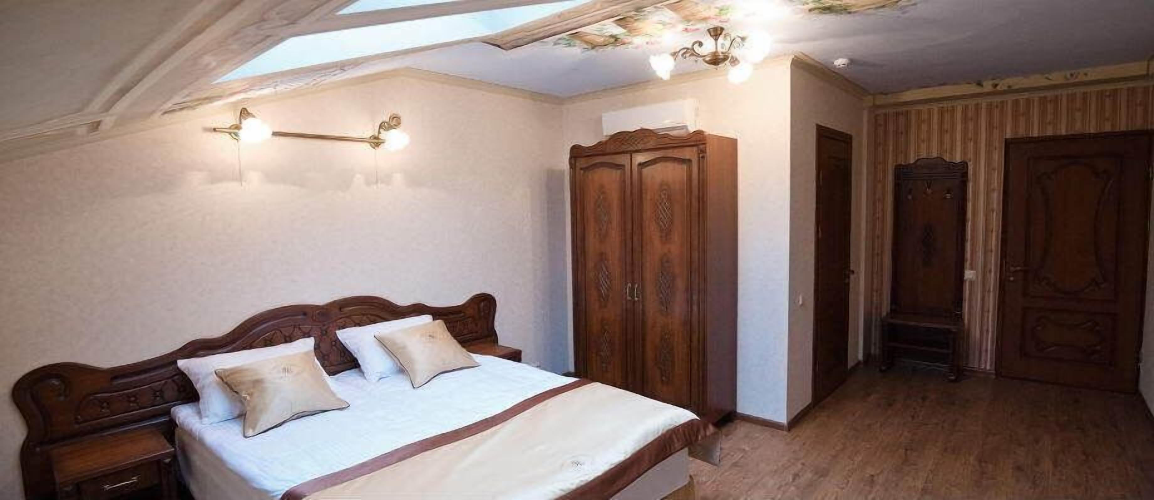 A bedroom with a wooden bed, a wardrobe, and a ceiling with a skylight.