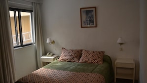 A bedroom with a bed, two bedside tables, a window with curtains, and a framed picture on the wall. - Hotel Bariloche Flat (Bariloche)