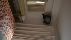 A narrow, enclosed space with a window, a small light fixture, and a patterned fabric on the left. - Hotel Bariloche Flat (Bariloche)