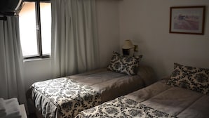 A bedroom with two beds, a window with curtains, a lamp, and a framed picture on the wall. - Hotel Bariloche Flat (Bariloche)
