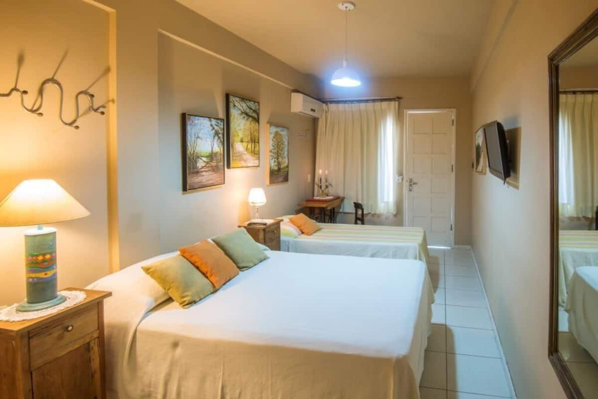 A hotel room with two beds, a desk, a chair, and a mirror.