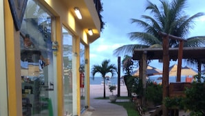 A stone-paved walkway leading to a building with glass doors and a yellow facade. - Pousada Funny (Morro de Sao Paulo)