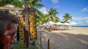 A beach area with wooden signage, palm trees, and beach umbrellas. - Pousada Funny (Morro de Sao Paulo)