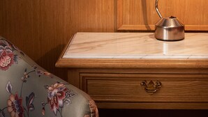 A wooden headboard with a floral-patterned wallpaper, a desk with a lamp, and a floral-patterned sofa. - Gran Hotel Ailen (Buenos Aires)