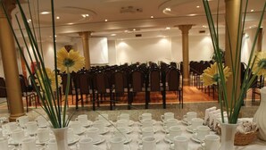 A conference room with rows of chairs, white vases with flowers, and a table set with white cups and saucers. - Gran Hotel Ailen (Buenos Aires)