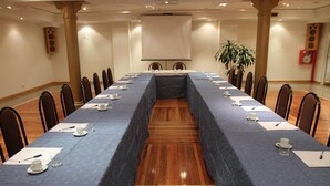 A conference room with a long table, chairs, a projector screen, and a plant. - Gran Hotel Ailen (Buenos Aires)