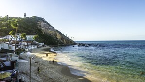 Un pueblo costero con un faro, playa y casas a lo largo de la orilla.