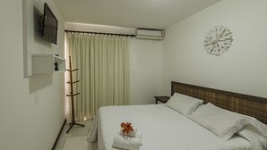 Habitación de hotel con cama, televisor montado en la pared, equipo de aire acondicionado, un adorno en la pared y una cortina.