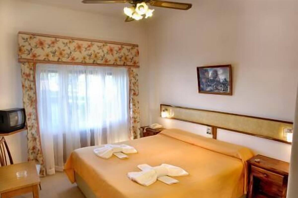 A hotel room with a bed, a television, a desk, and a chair.