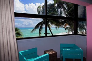 A room with a large window overlooking a beach with palm trees and the ocean. - All Riviera (Playa del Carmen)