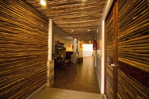 A corridor with wooden paneling on the walls and ceiling, leading to a room with a tiled floor and a visible door. - All Riviera (Playa del Carmen)