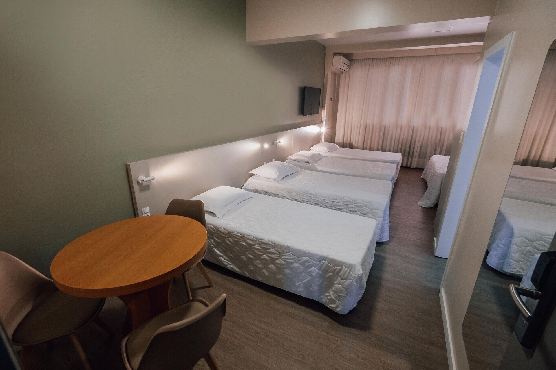 Une chambre d’hôtel avec deux lits, une petite table ronde et une chaise.