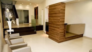 Una moderna area reception con scrivania in legno, una scala e un angolo relax con poltrone.