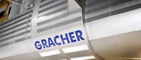 A hotel entrance with a sign reading "GRACHER HOTEL" and a modern facade with glass doors.