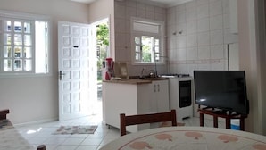 A kitchen with a TV, a dining table, and a window. - Pousada Belo Mar (Florianopolis)