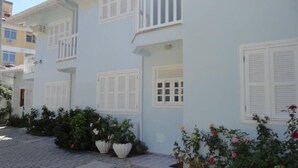 A light blue building with white shutters, a balcony, and potted plants. - Pousada Belo Mar (Florianopolis)