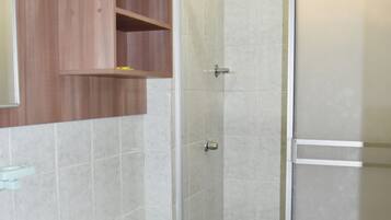 Un baño con inodoro, lavamanos y cabina de ducha.