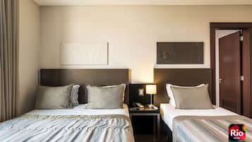 Habitación de hotel con dos camas, una mesita de noche con lámpara y obras de arte en las paredes.