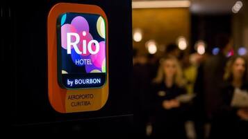 Placa do Hotel Rio by Bourbon, com um logotipo colorido e o nome 'AEROPORTO CURITIBA'.