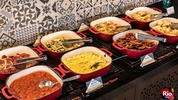 Un bufé con diversos platos, entre ellos huevos revueltos, frijoles y tocino.