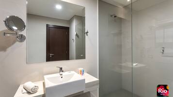 A modern bathroom with a glass shower enclosure, a white sink, and a mirror.