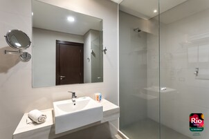 Un baño moderno con cabina de ducha de vidrio, un lavabo blanco y un espejo.