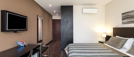 Ein Hotelzimmer mit Bett, Nachttisch, Fernseher und Minibar.